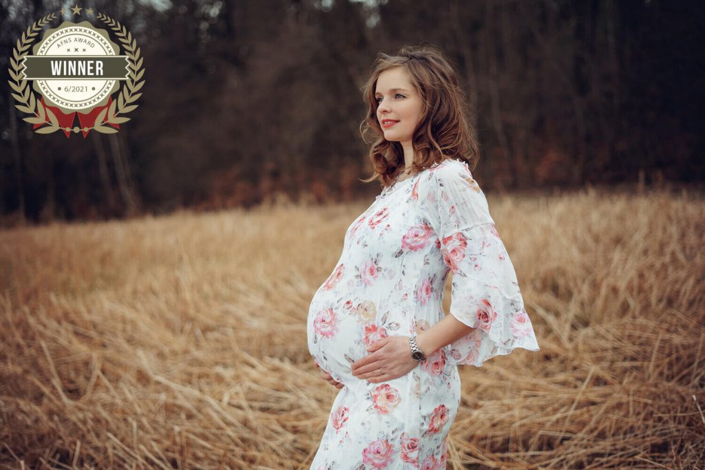 Schwangere Frau steht in einem Feld