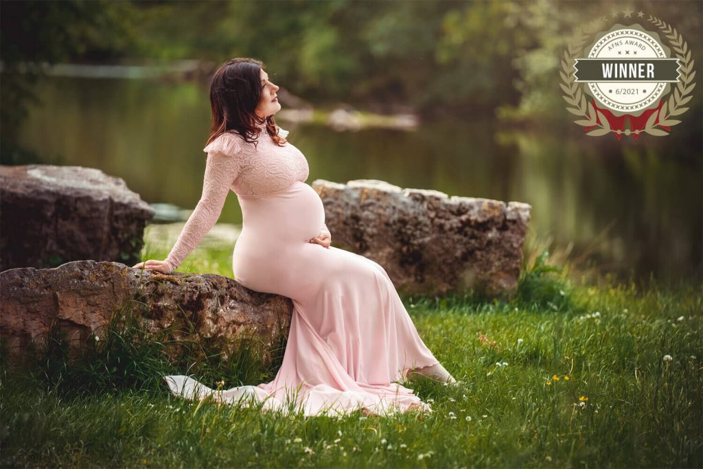 Schwangere Frau sitzt auf einem Stein